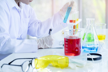 Fototapeta premium Scientist hand holding a Test tubes, Focused female researcher with dropper in chemical lab.