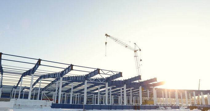 Modern storehouse construction site, the structural steel structure of a new commercial building against a clear blue sky in the background, Construction of a modern factory or warehouse