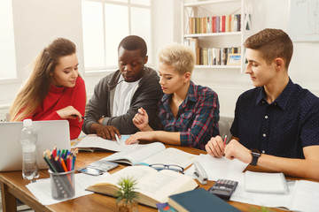 Group of diverse students studying at wooden table