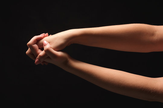 Woman holding hands together at black isolated background