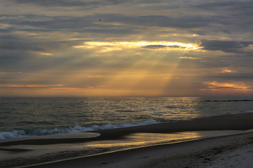 Sun rays cutting thru clouds on to the ocean during golden hour on long island