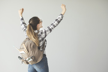 Female student arms raised with backpack on grey background