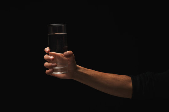 Male Hand Holding Glass Of Water Isolated On Black