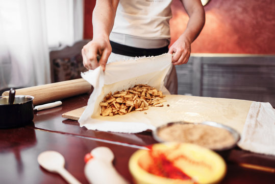 Chef wraps the filling into dough, apple strudel 