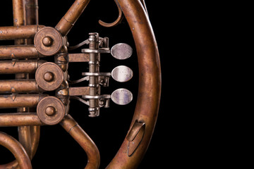 Vintage bronze pipes, valve, key mechanical elements french horn, black background. Good pattern,...
