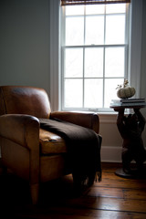 Old leather chair by the window with a stand on a side 