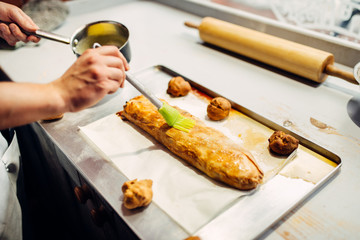 Chef lubricates strudel, preparation for baking