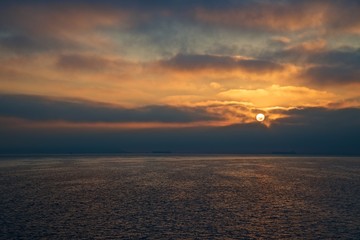 Colored sunset sky with beauty clouds and sun rays. Abstract seascape.