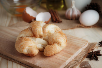 Croissant on wooden cut board on table wood and fabric select focus shallow depth of field