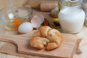 Croissant on wooden cut board on table wood and fabric select focus shallow depth of field