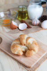 Croissant on wooden cut board on table wood and fabric select focus shallow depth of field