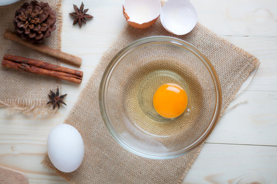 Egg on clear glass bowl over wooden cut board with bakery ingredients select focus shallow depth of field