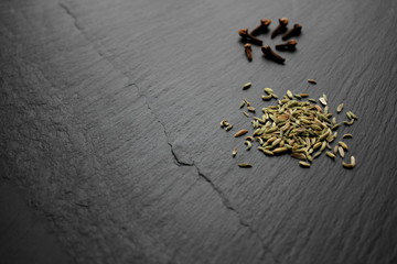 Fennel seeds and cloves on slate board, copy space