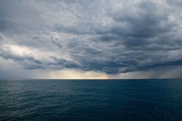 Obraz premium Stormy weather in the sea. Heavy dark clouds over the water. Stripes of rain. A thunderstorm is coming. Beautiful seascape.