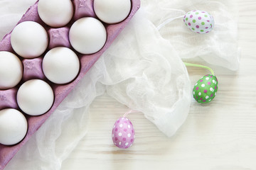 Top view of white eggs and pink colored Easter eggs r on white wooden background. Top view, Easter concept, greeting card