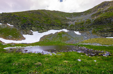 little swamp under the hill with patch of snow. lovely springtime nature background
