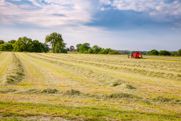 Summer rural landscape with tractor collecting hay in the field Southern England UK