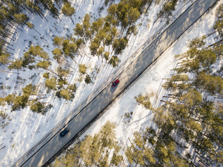 Snowy road with a moving car in winter. Aerial photography
