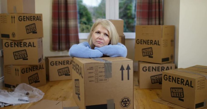 4K Depressed woman surrounded by boxes in house move
