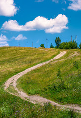 country road along the hillside. lovely countryside rural scenery in summer. beautiful blue summer sky with fluffy clouds