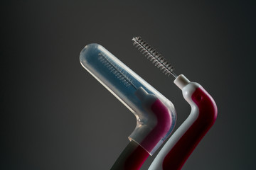 Interdental brush with opened cover isolated on dark background with copy space. Dental care concept. Equipment for get rid of food stuck in teeth