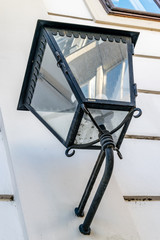 Old street lamp on the wall. The façade of a building is reflected in a lamp.
