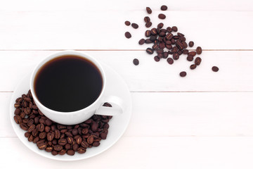 Top view of a white cup with coffee on a white wooden background.