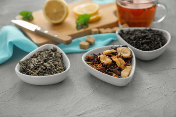 Bowls with different types of dry tea leaves on table
