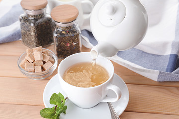 Pouring hot tea into cup on table