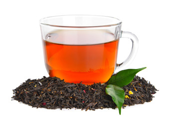 Dry black tea leaves and cup of aromatic beverage on white background