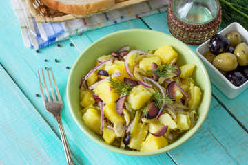 Vegetarian breakfast in a bowl of potatoes, marinated cucumbers, onions and olives on a wooden table in a rustic style. Diet, concept of vegetarian food.