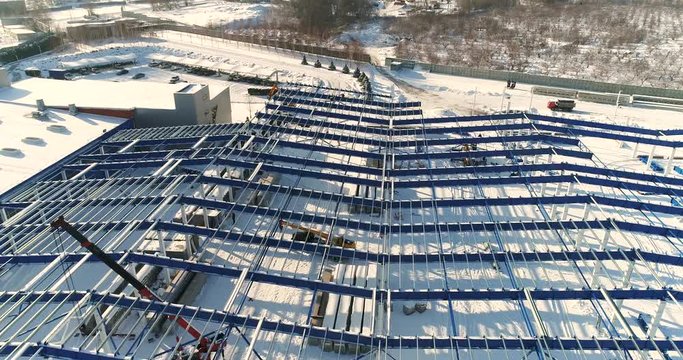 Construction of a modern factory or plant, Industrial area in winter, panoramic view from the air. Modern plant on the snow-covered field, the structural steel structure of a new commercial building