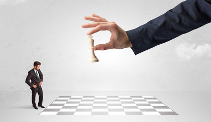 Fototapeta premium Little businessman playing chess with a big hand concept