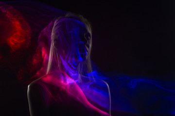 Conceptual avant-garde silhouette portrait of a beautiful blonde girl covered with multicolored lines applied by a lightbrush