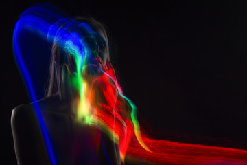 Conceptual avant-garde silhouette portrait of a beautiful blonde girl covered with multicolored lines applied by a lightbrush