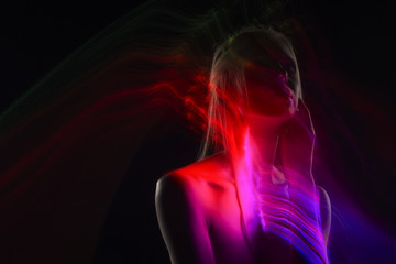 Conceptual avant-garde silhouette portrait of a beautiful blonde girl covered with multicolored lines applied by a lightbrush