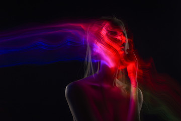 Conceptual avant-garde silhouette portrait of a beautiful blonde girl covered with multicolored lines applied by a lightbrush