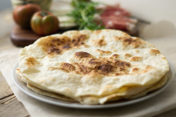 Homemade Italian flatbread called piadina with rocket salad, prosciutto and ricotta cheese.