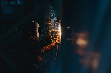 Man welder at work sparks wall metal welding