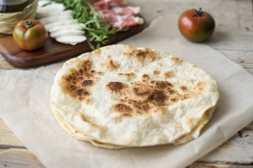 Homemade Italian flatbread called piadina with rocket salad, prosciutto and ricotta cheese.