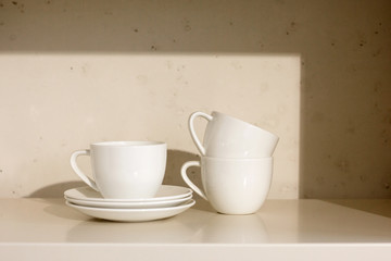 Fototapeta na wymiar white ceramic cups and saucer on a shelf