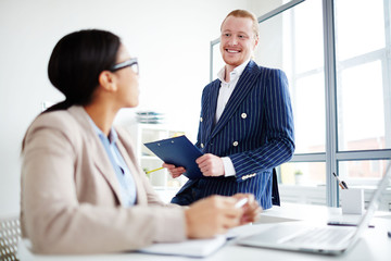 Obraz premium Smiling businessman communicating with his colleague at office