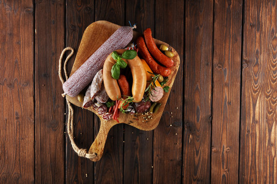 Food tray with delicious salami, ham,  fresh sausages, cucumber and herbs. Meat platter
