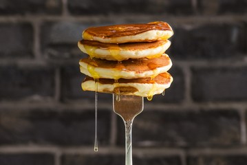 Pancake with liquid honey on brick background. Selective focus.