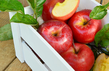 Red apple or Gala apple group with slice and water drop in white wooden box on wooden background