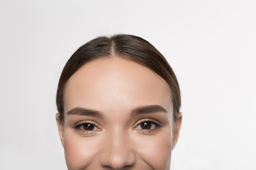 Happy look. Close-up of positive young woman with beautiful eyes are looking at camera with joy. Isolated background