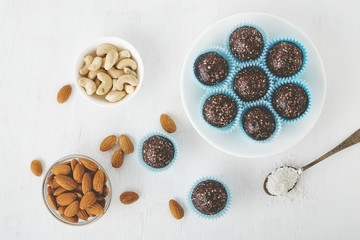 Healthy chocolate energy bites with nuts, dates, cocoa powder, coconut flakes on white table. - 196891905