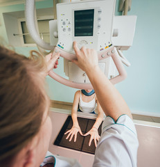 Radiologist and patient in a x-ray room. Classic ceiling-mounted x-ray system.