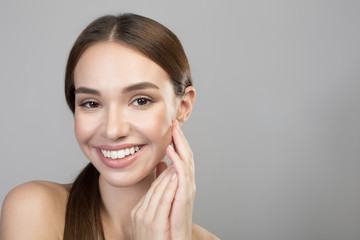 My soft skin. Portrait of optimistic gorgeous naked woman is touching her face while looking at camera with joy and expressing satisfaction. Skincare and beauty concept. Isolated and copy space