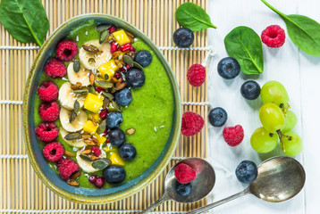 Green avocado, spinach and grape smoothie garnished with fresh fruit